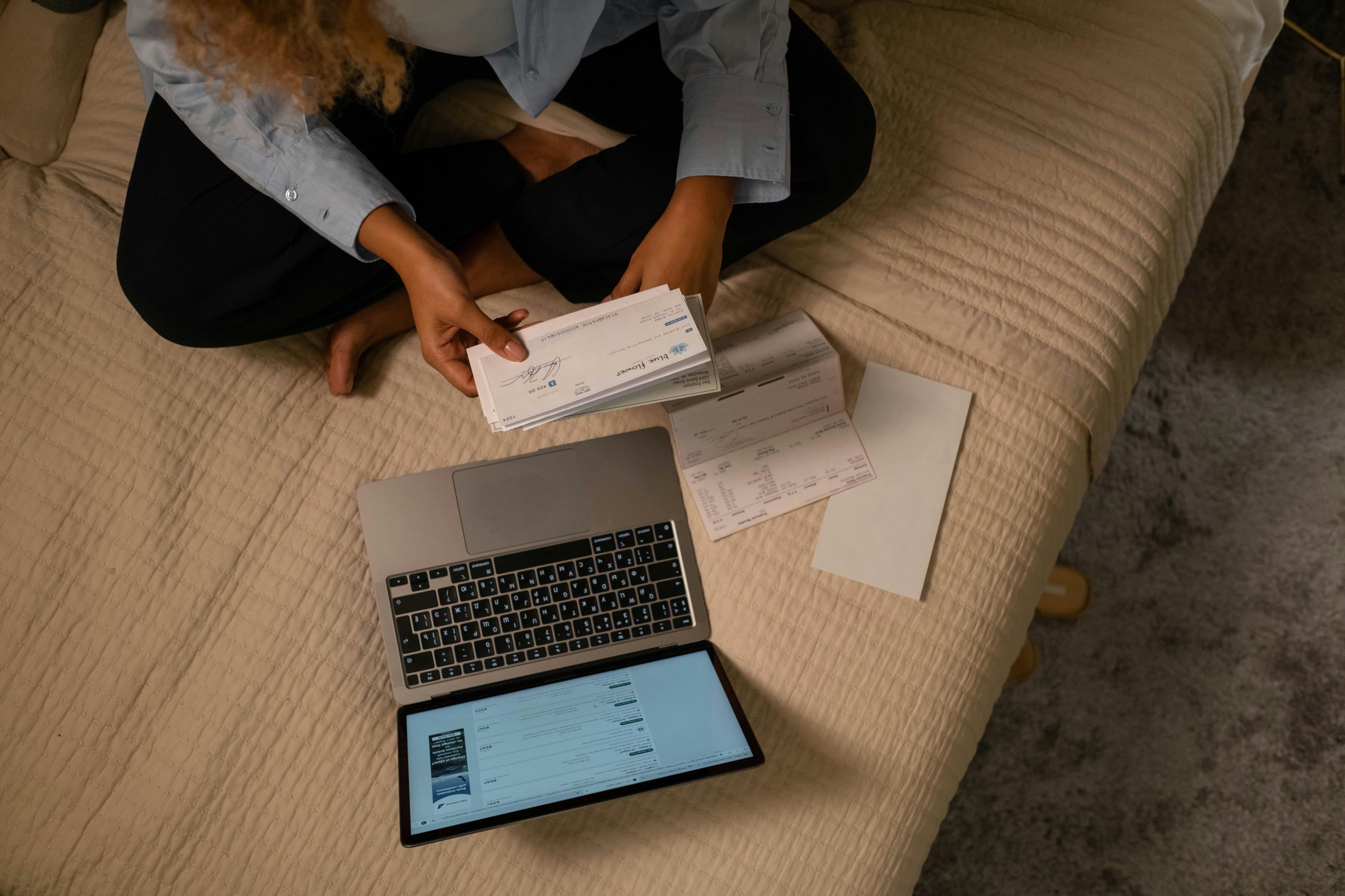 Small business owner looking stressed at an expensive invoice next to her laptop